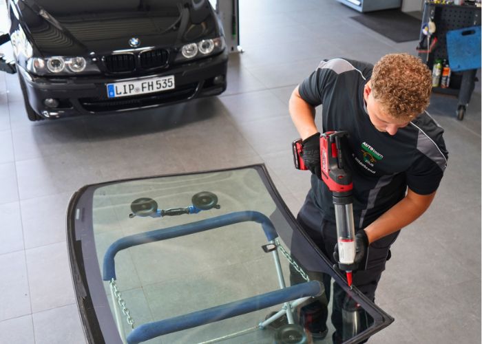 Werkstatt Mitarbeiter wechselt Frontscheibe an einem Fahrzeug.