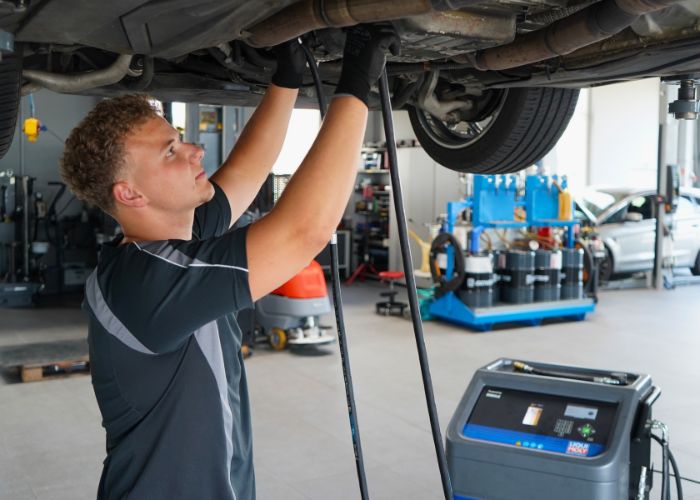 Werkstatt Mitarbeiter wechselt Automatik-Getriebeöl an einem Fahrzeug.