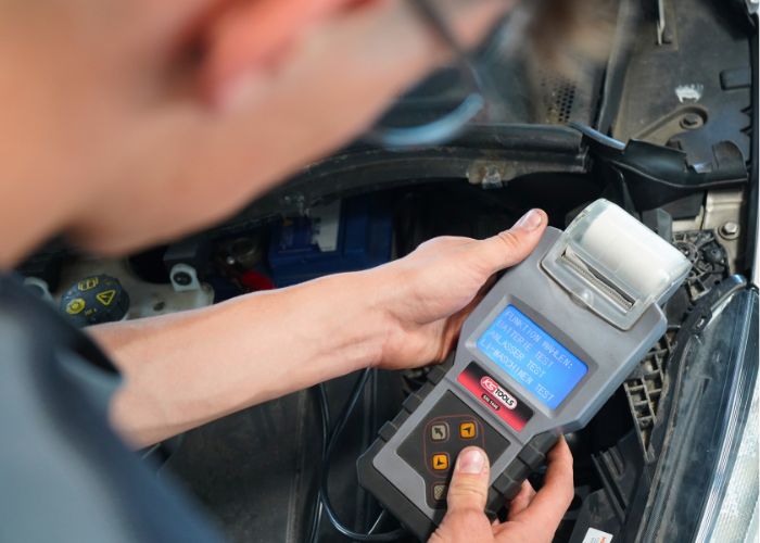 Mitarbeiter führt in der Kfz-Werkstatt einen Batteriecheck durch.