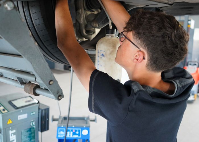 Werkstatt Mitarbeiter wechselt Bremsenflüssigkeit an einem Fahrzeug.
