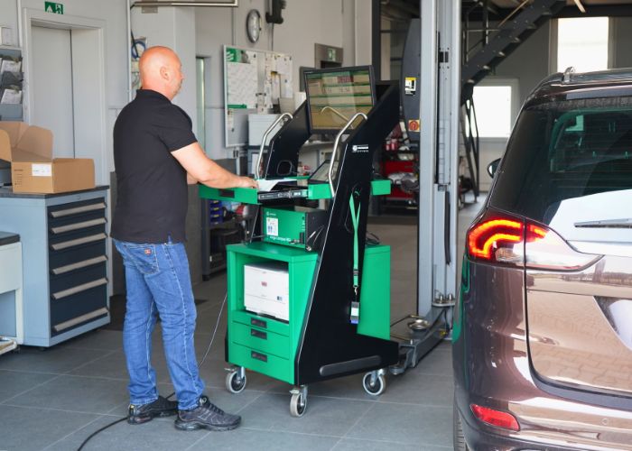 Werkstatt Mitarbeiter führt Abgasuntersuchung an einem Fahrzeug durch.