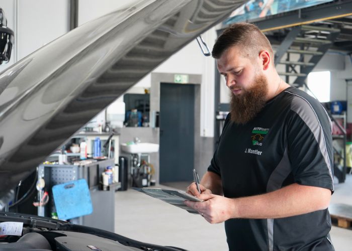 Mitarbeiter führt in der Kfz-Werkstatt eine Inspektion nach Herstellervorgaben durch.