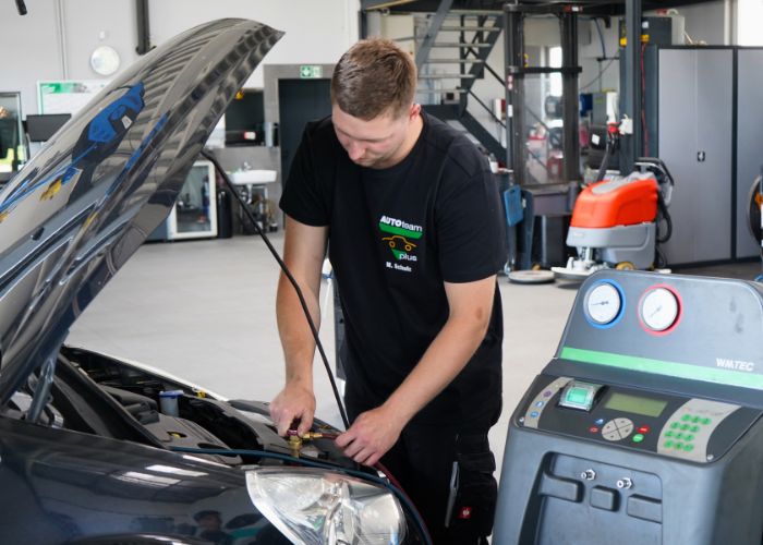 Mitarbeiter führt in der Kfz-Werkstatt einen Klimaservice durch.