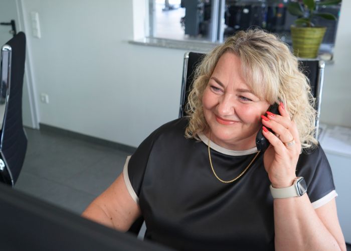 Mitarbeiterin sitzt am Empfang und berät einen Kunden telefonisch.