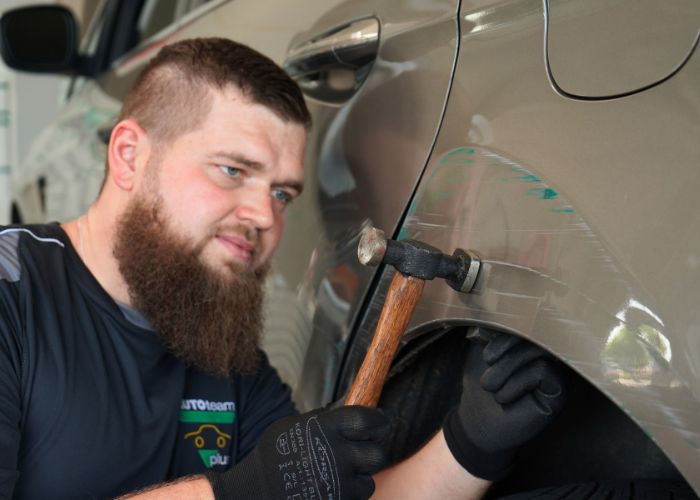 Werkstatt Mitarbeiter repariert Karosserie von einem Fahrzeug in Kfz-Werkstatt in Augustdorf.