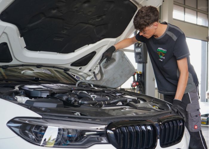 Mitarbeiter führt in der Kfz-Werkstatt einen Sommercheck durch.